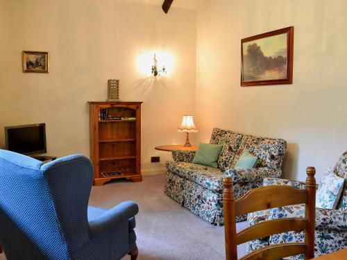 ein Wohnzimmer mit einem Sofa und einem Stuhl in der Unterkunft Lavender Cottage-mgg in Akeld