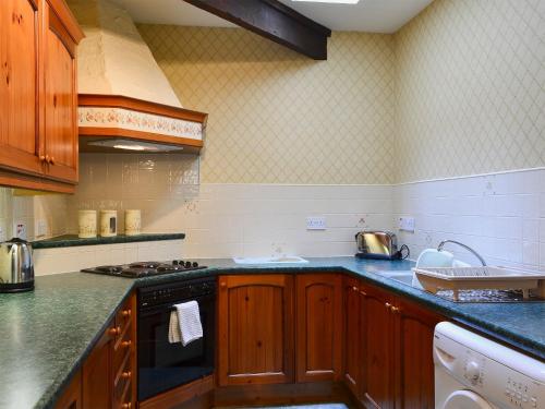 cocina con armarios de madera y horno con fogones en Lavender Cottage-mgg, en Akeld