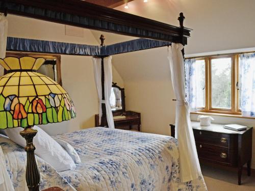 a bedroom with a canopy bed with a lamp at Baldash Lodge in Branscombe