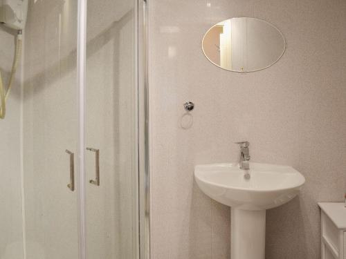 a bathroom with a sink and a shower with a mirror at Sea View in Shilbottle