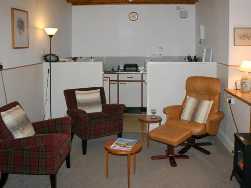 a living room with three chairs and a kitchen at Bakehouse Cottage in Balnald