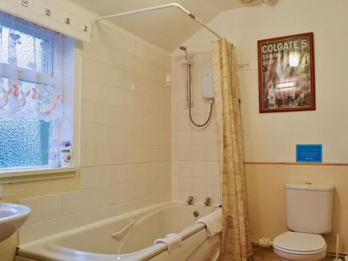 a bathroom with a tub and a toilet and a sink at Bakehouse Cottage in Balnald