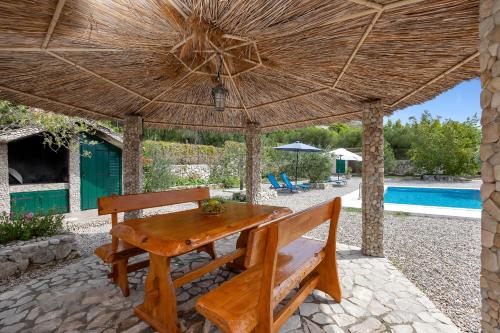 a wooden table and bench under a large umbrella at Villa Natura Makarska in Makarska