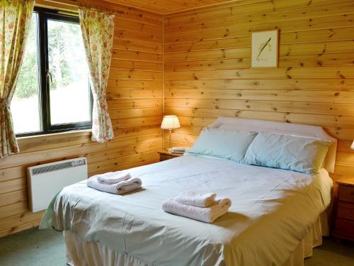 ein Schlafzimmer mit einem Bett in einem Blockhaus in der Unterkunft Larch Cottage - S4428 in Kirkton of Glenisla