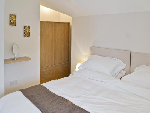 um quarto com uma cama branca e um armário de madeira em Baytree Cottage 2 em Birch
