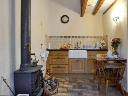 eine Küche mit einem Herd und einem Tisch darin in der Unterkunft The Pig Sty in Llanfair-ar-y-bryn