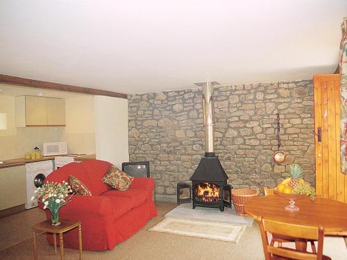 a living room with a red couch and a fireplace at Challeys Cottage - E2378 in Banwell
