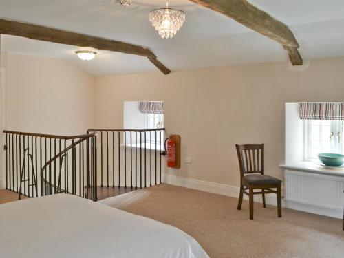 a bedroom with a bed and a chair at Plover Cottage in Sharperton