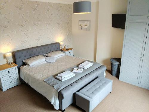 a bedroom with a large bed with a bench next to it at Wren Cottage in Longhorsley