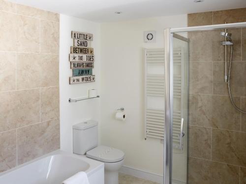 a bathroom with a tub and a toilet and a shower at Manor Cottage in Crantock