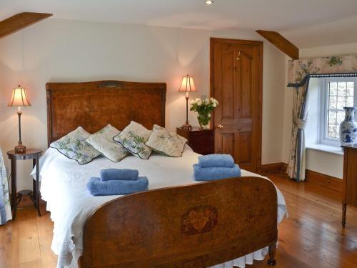 a bedroom with a large bed with blue pillows at Grooms Cottage in Westleigh