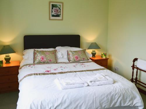 um quarto com uma grande cama branca com toalhas em The Cottage em Poolewe