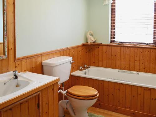 a bathroom with a toilet and a bath tub at The Cottage in Poolewe