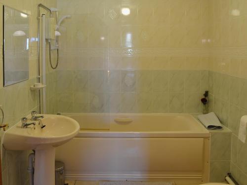 a bathroom with a sink and a bath tub and a sink at Dwyfach in Llanystumdwy