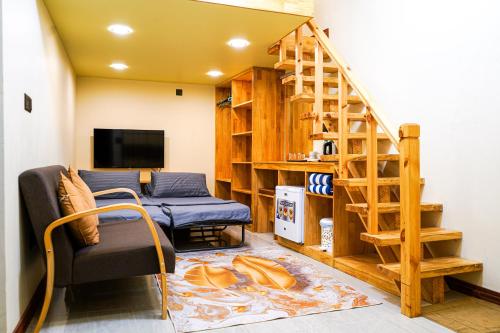 a living room with a staircase and a couch and a television at Banyan Villa Maldives Dhangethi in Dhangethi