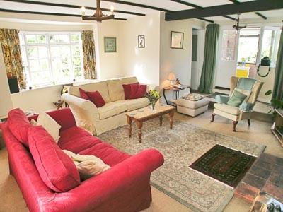 ein Wohnzimmer mit einem roten Sofa und Stühlen in der Unterkunft Bay House in Sculthorpe