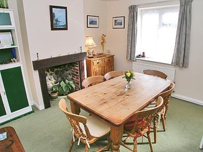 a dining room with a table and chairs and a fireplace at Bay House in Sculthorpe
