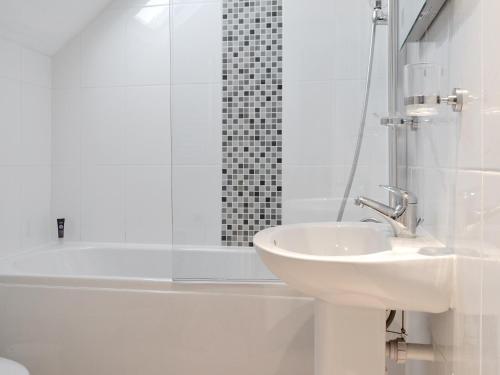 La salle de bains blanche est pourvue d'un lavabo et d'une douche. dans l'établissement Blencathra, à Keswick