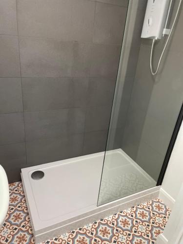 a shower with a glass door in a bathroom at Moonlight Lodge in Caeathro