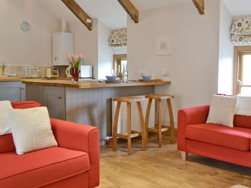 a kitchen with two red chairs and a counter at The Vestry in Cyffic