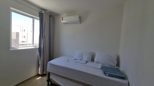 uma cama com almofadas brancas e uma janela num quarto em Casa praia do Francês em Marechal Deodoro