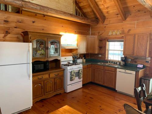 a kitchen with wooden cabinets and a white refrigerator at Cozy Creekside Cabin in the heart of Hocking Hills in Laurelville