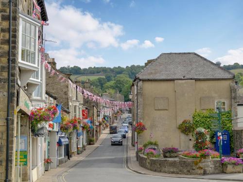 a street in a small town with flowers on buildings at Grisedale Stables Cottage in Threshfield