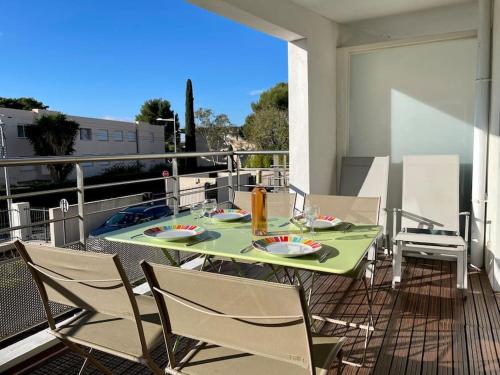 d'une table et de chaises vertes sur un balcon dans l'établissement 17 - Appartement neuf, parking terrasse et jolie vue, à Bandol