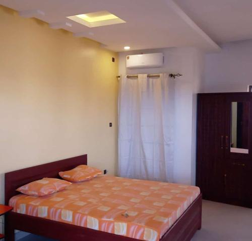 - une chambre avec un lit doté de draps orange et une fenêtre dans l'établissement Résidence Vauvert, à Saint-Louis