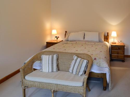 a bedroom with a bed with a wicker chair with pillows at The Old Cowshed in Broadway