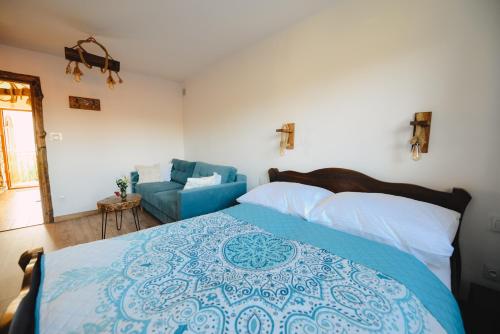 a bedroom with a large bed and a blue couch at Apartament Zielony Ruczaj w Cisnej in Cisna