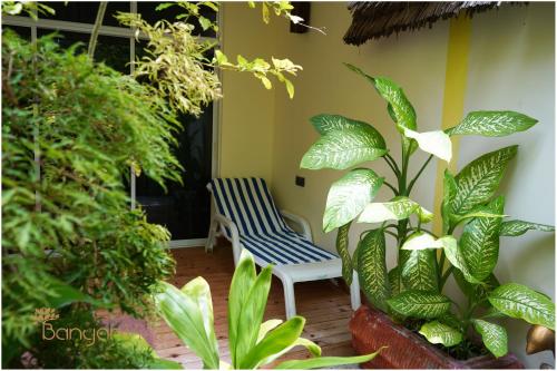 a chair sitting in a room with plants at Banyan Villa Maldives Dhangethi in Dhangethi