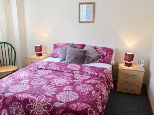 a bedroom with a purple bed with two night stands at Kimberly Cottage in Alness