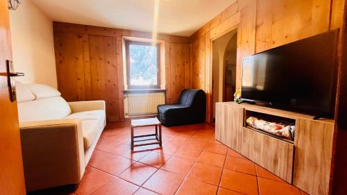 uma sala de estar com um sofá e uma televisão de ecrã plano em PredazzoHouse em Predazzo