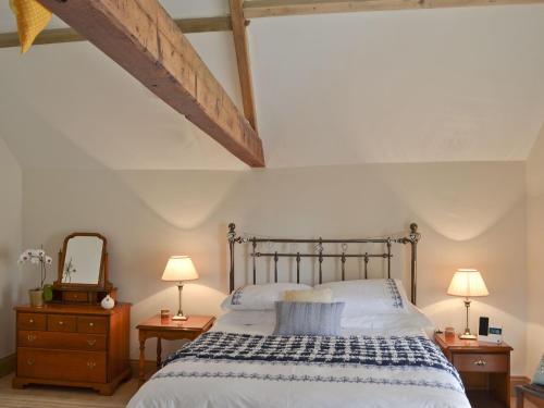 um quarto com uma cama e duas mesas de cabeceira e um espelho em Manor House Dairy Cottage em Ayton