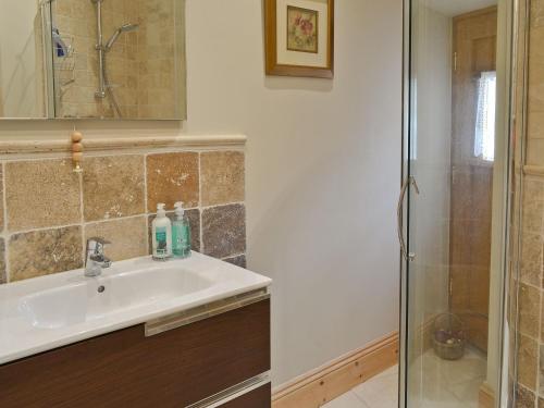 uma casa de banho com um lavatório e um chuveiro em Manor House Dairy Cottage em Ayton
