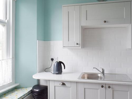 a kitchen with white cabinets and a sink at Mere View in Ambleside