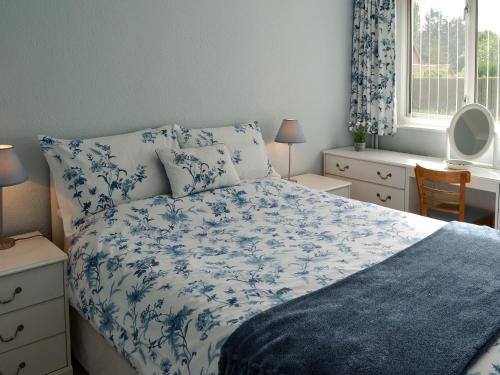 a bedroom with a blue and white bed and a window at The Mount in Boxford