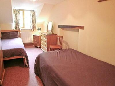 a bedroom with two beds and a dresser and a desk at Denhill Cottage in Chipstable