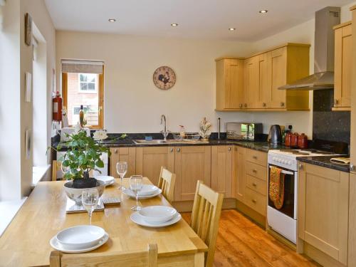 Chestnut Cottage-27565 في Botesdale: مطبخ مع طاولة خشبية وغرفة طعام