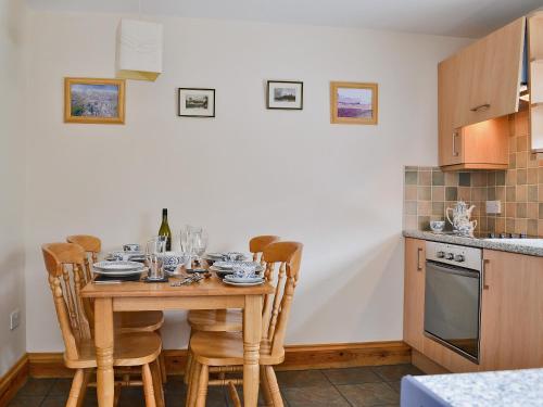 a kitchen with a wooden table and chairs in a kitchen at Elens Place in Tywyn