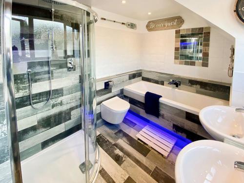 a bathroom with a shower and a tub and a sink at Coombehayes Barn in Uplyme