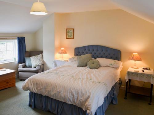 a bedroom with a large bed and a chair at Watercolour Cottage in Lerryn