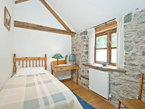 a bedroom with a bed and a desk with a tv at Llofft Stabal in Llanerfyl