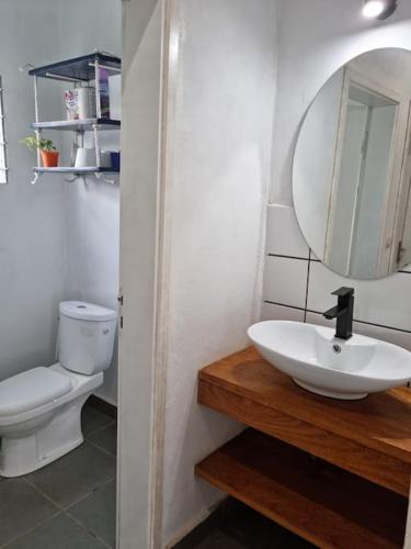 a bathroom with a sink and a toilet and a mirror at Résidence Le Verger, 2ch, Kribi in Kribi