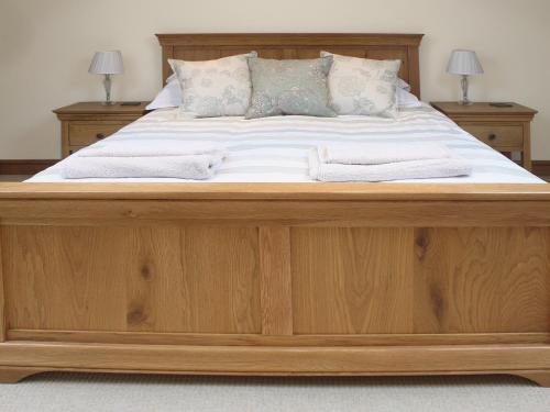a large wooden bed with two towels on it at Barn Owl Cottage in Sudbourne