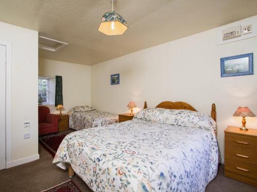 a bedroom with two beds and a chair at Katys Cottage in Balnaboth