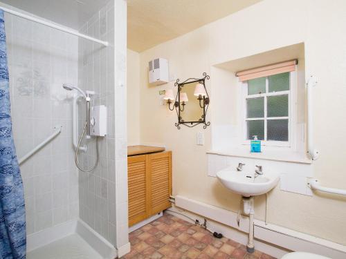 uma casa de banho com um chuveiro e um lavatório. em Katys Cottage em Balnaboth