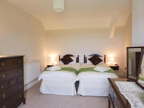 a bedroom with two beds and a dresser and a mirror at Rhiwgoch - Hw7449 in Harlech