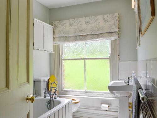 uma casa de banho com um lavatório, um WC e uma janela. em Sunnybank em Saint Margaret